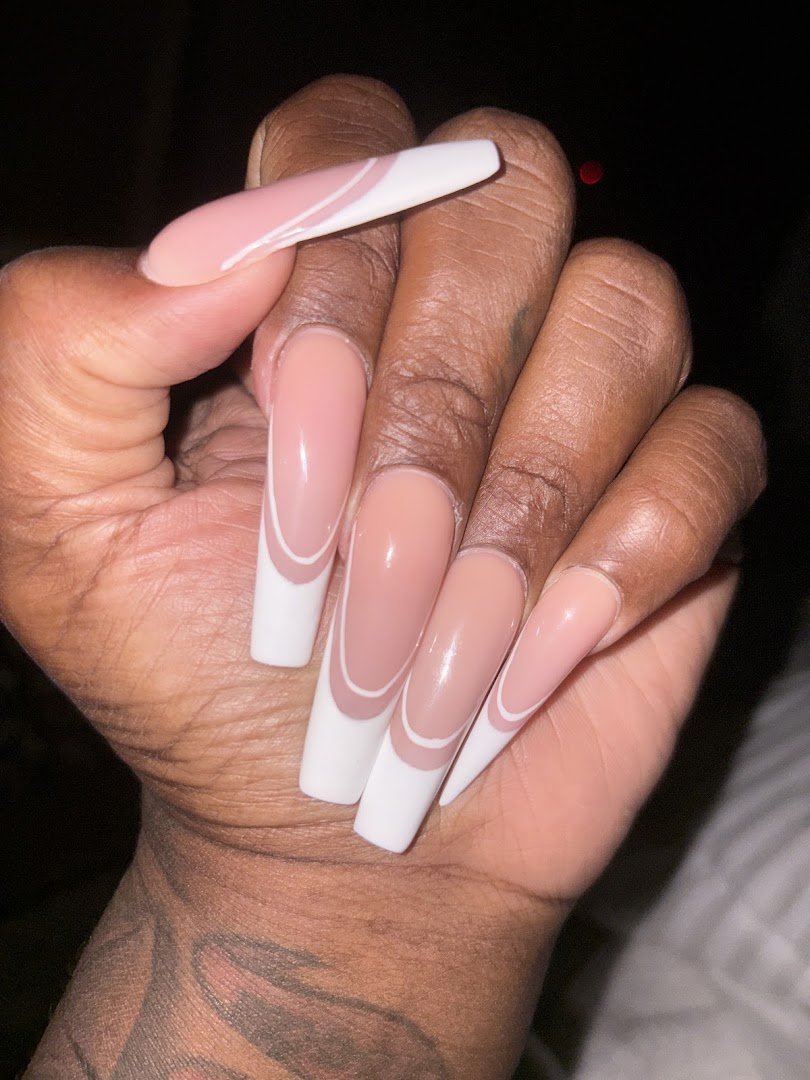 Nail technician shaping nails at a salon station.